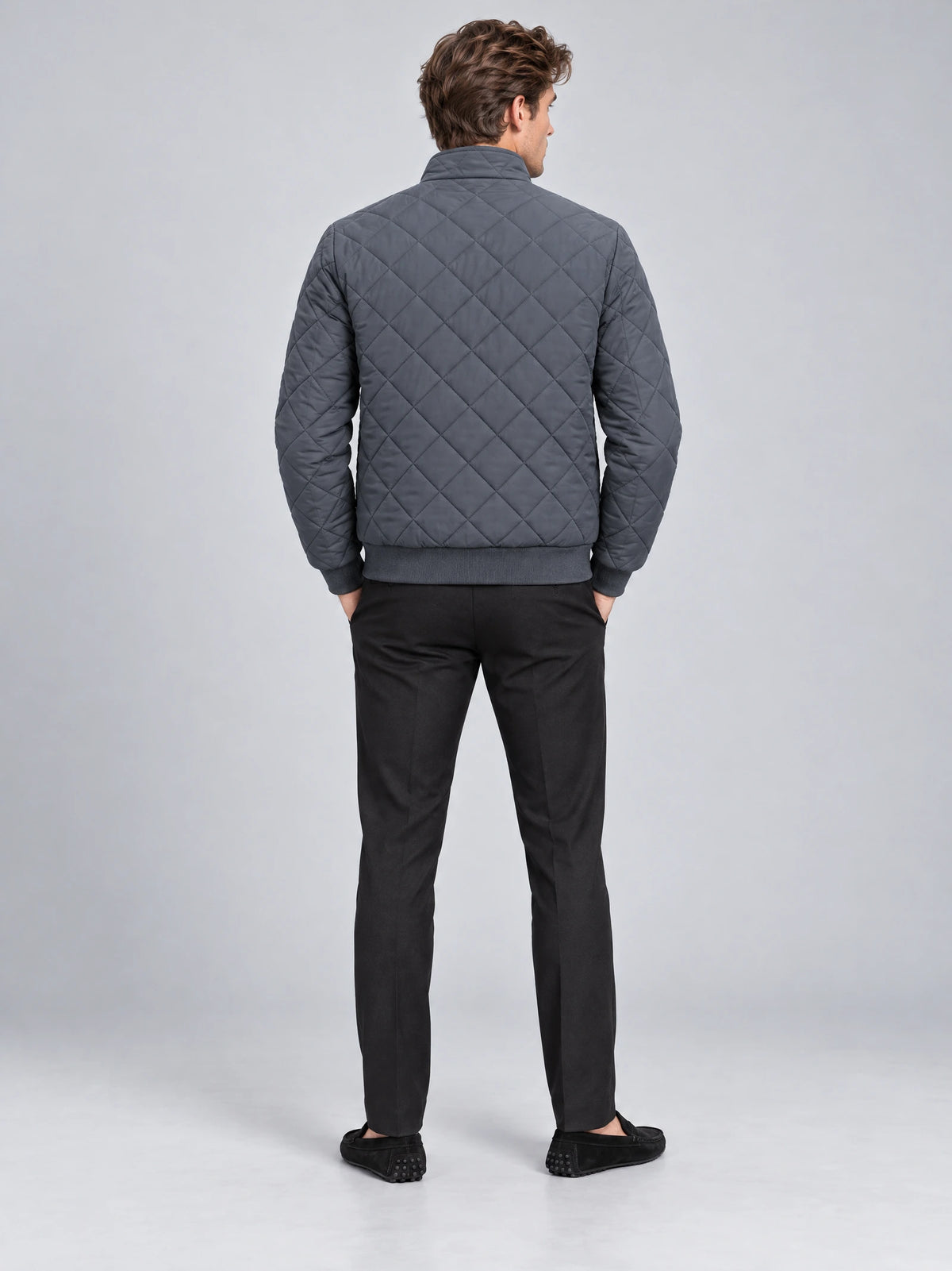 Rear view of a model wearing a Gray Winter Bomber Jacket with diamond quilting, ribbed hem, and cuffs.