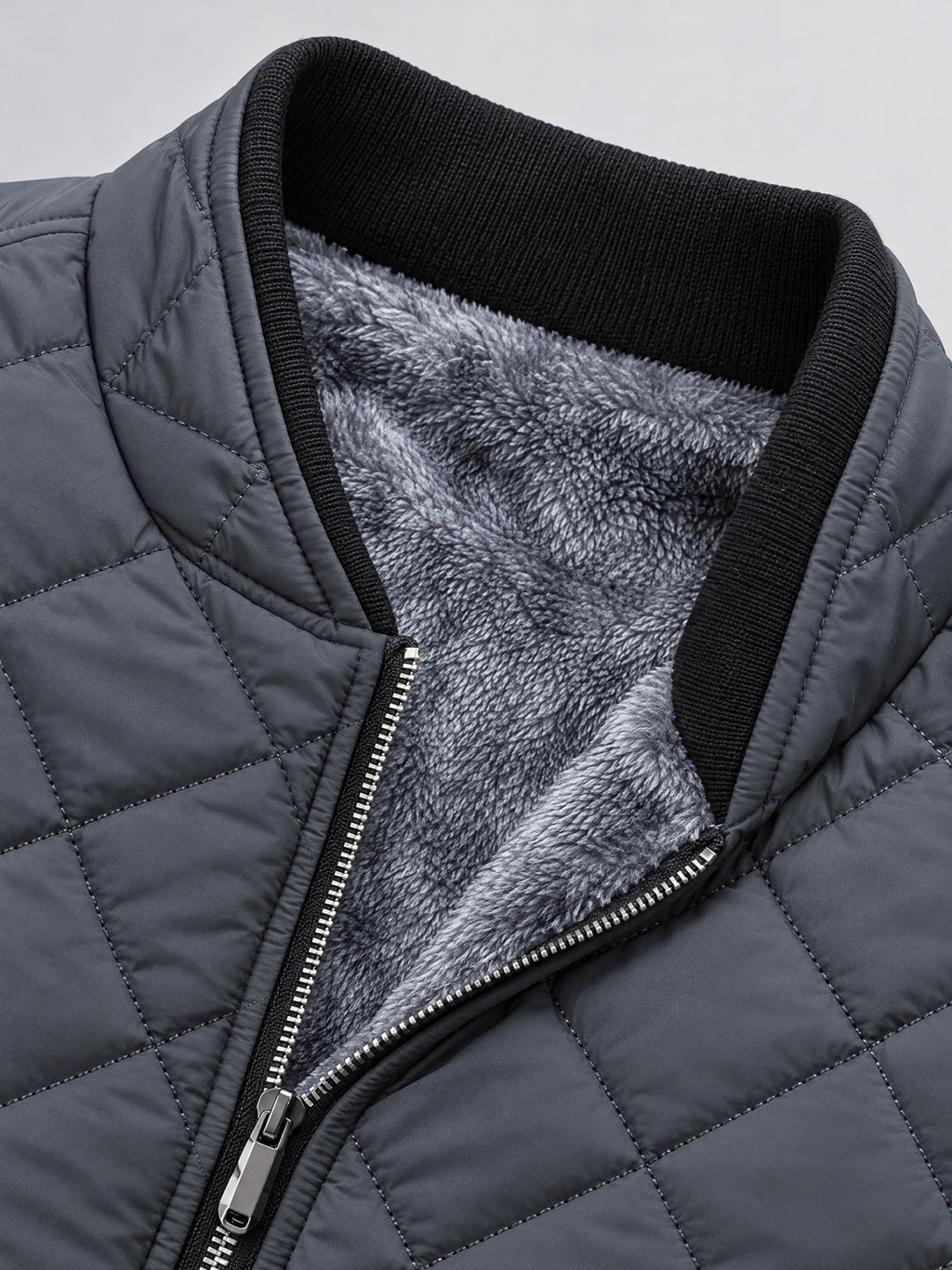 Gray Winter Bomber Jacket close-up showing diamond quilting, ribbed collar, front zipper, and soft fleece lining.