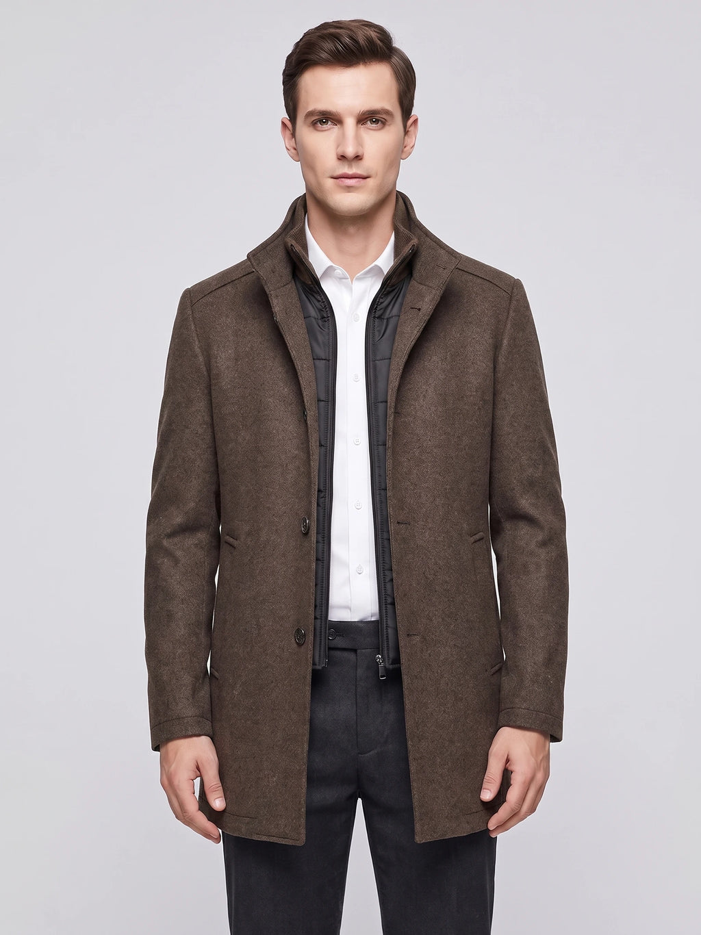 Front studio view of a model wearing a Brown wool overcoat with a stand collar, button front, and zip-in inner bib.