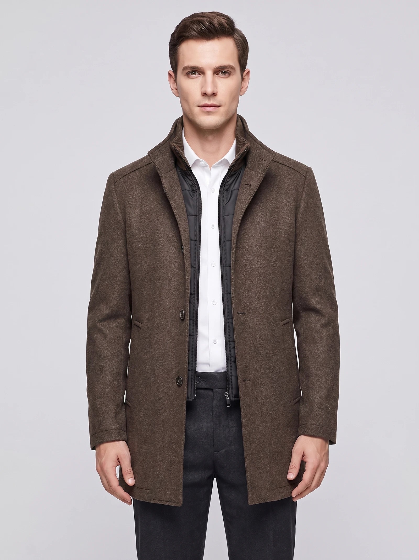 Front studio view of a model wearing a Brown wool overcoat with a stand collar, button front, and zip-in inner bib.