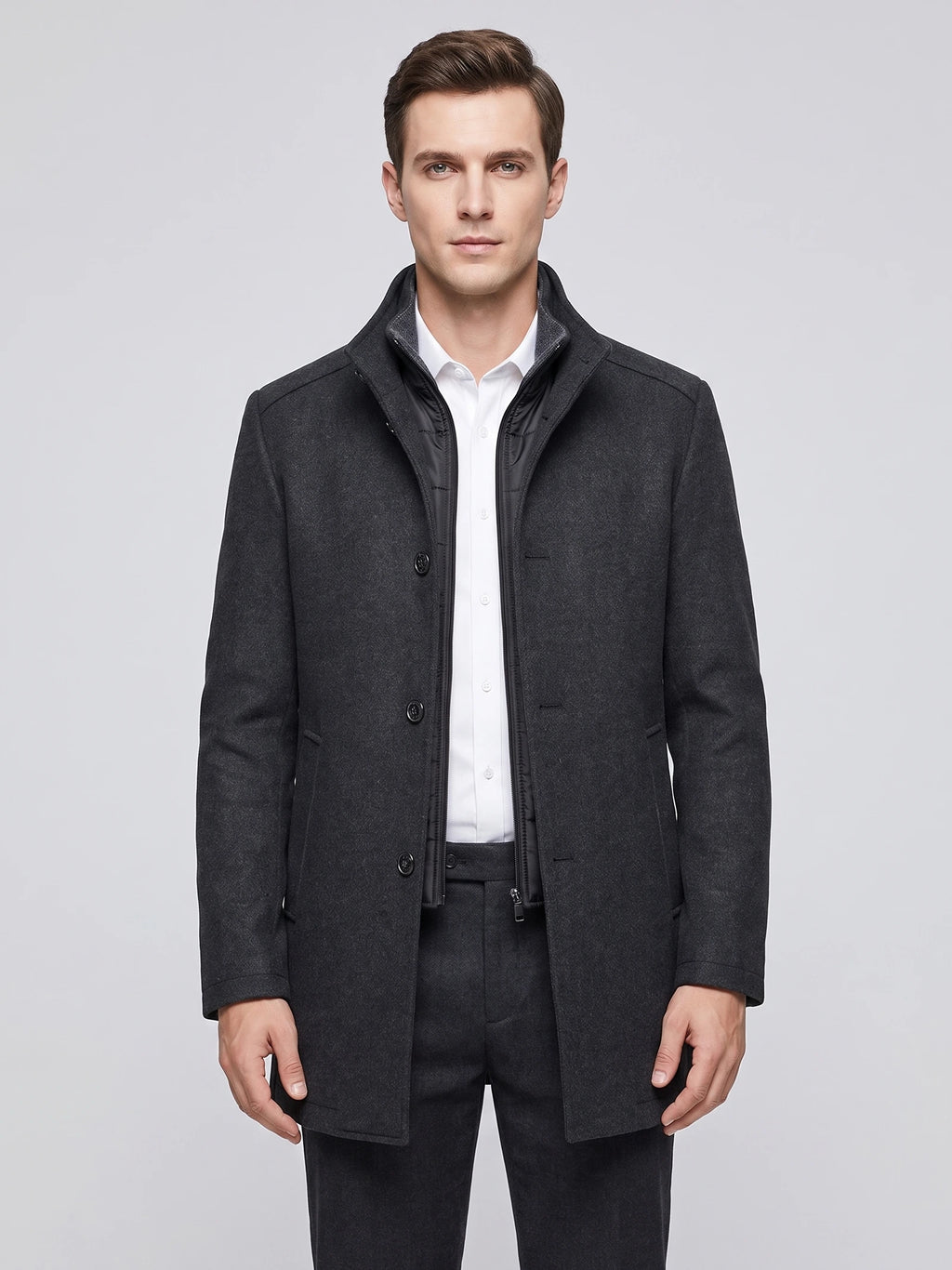 Front studio view of a model wearing a Gray wool overcoat with a stand collar, button front, and zip-in inner bib.