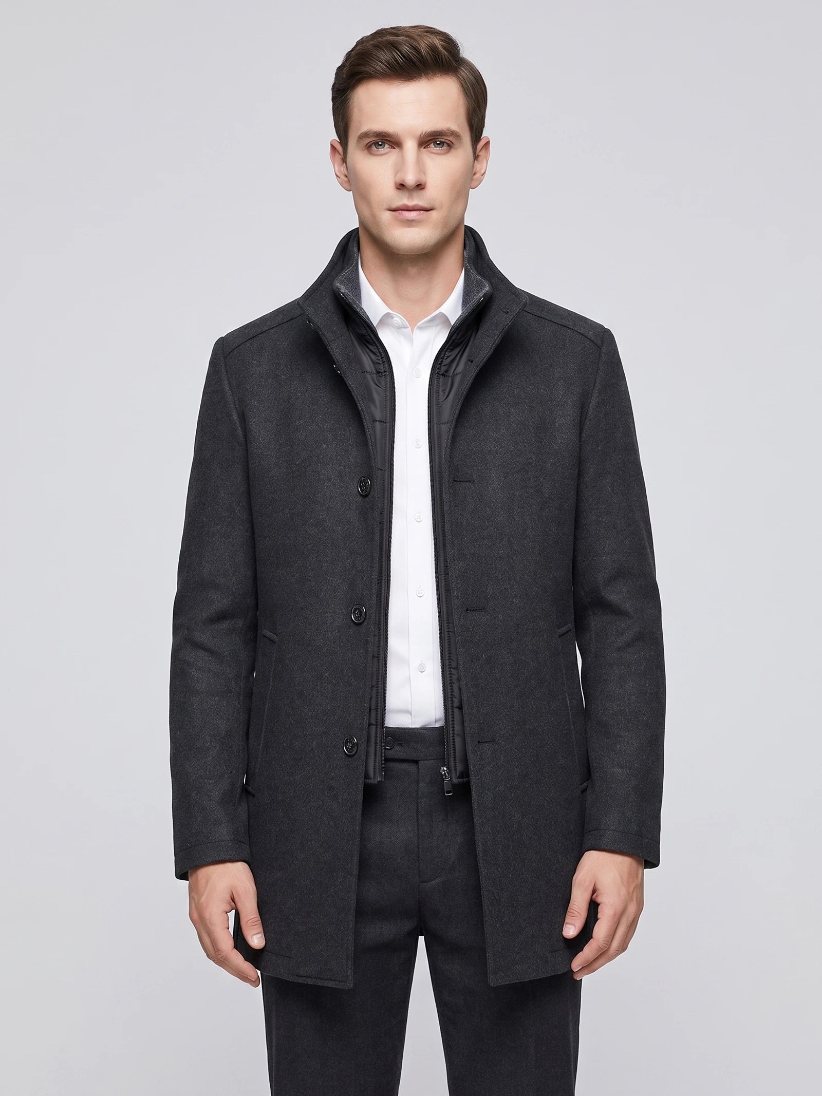 Front studio view of a model wearing a Gray wool overcoat with a stand collar, button front, and zip-in inner bib.