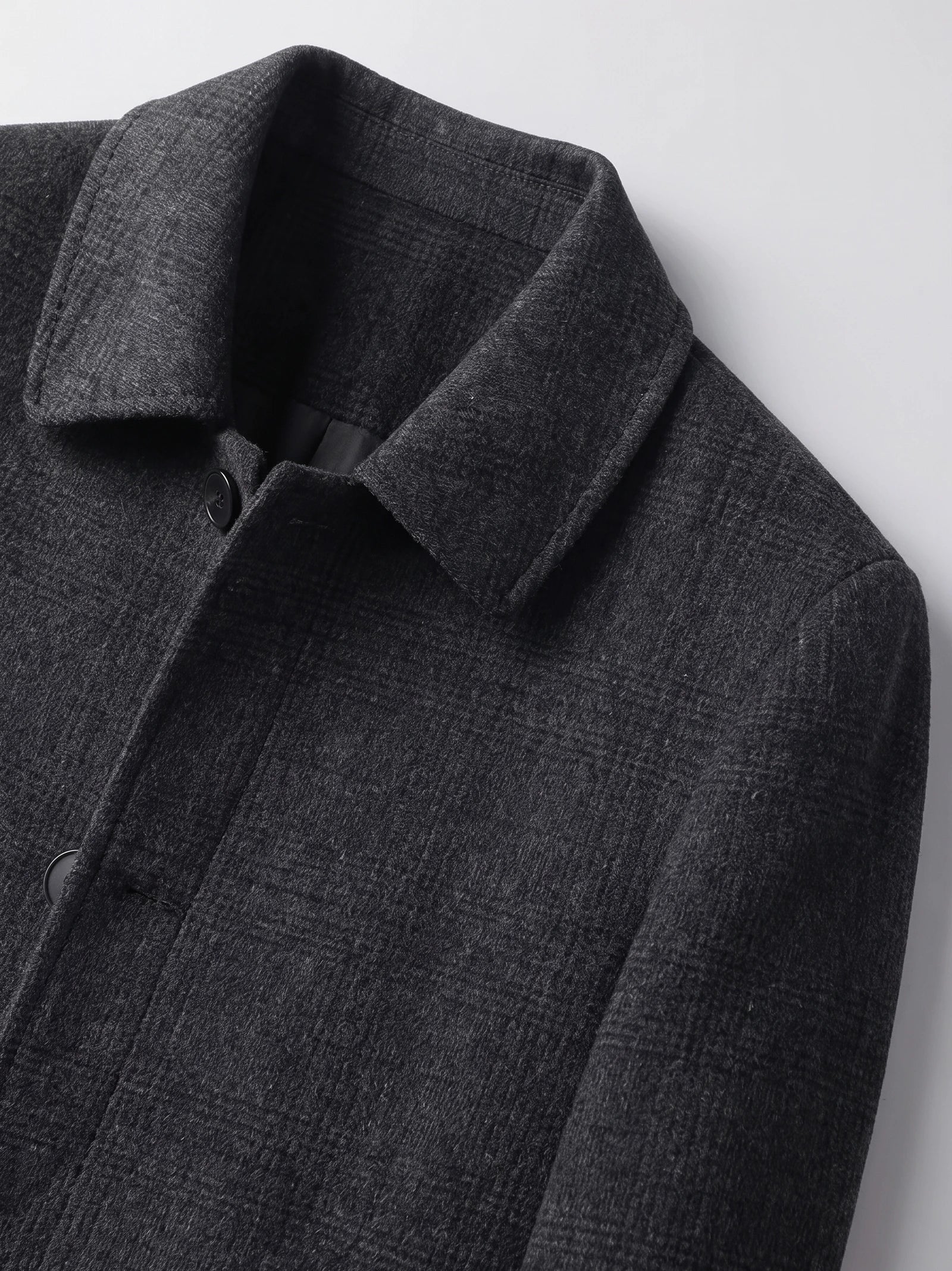 Close-up of the Black men's wool trench coat showing the pointed collar, button closure, and textured fabric.