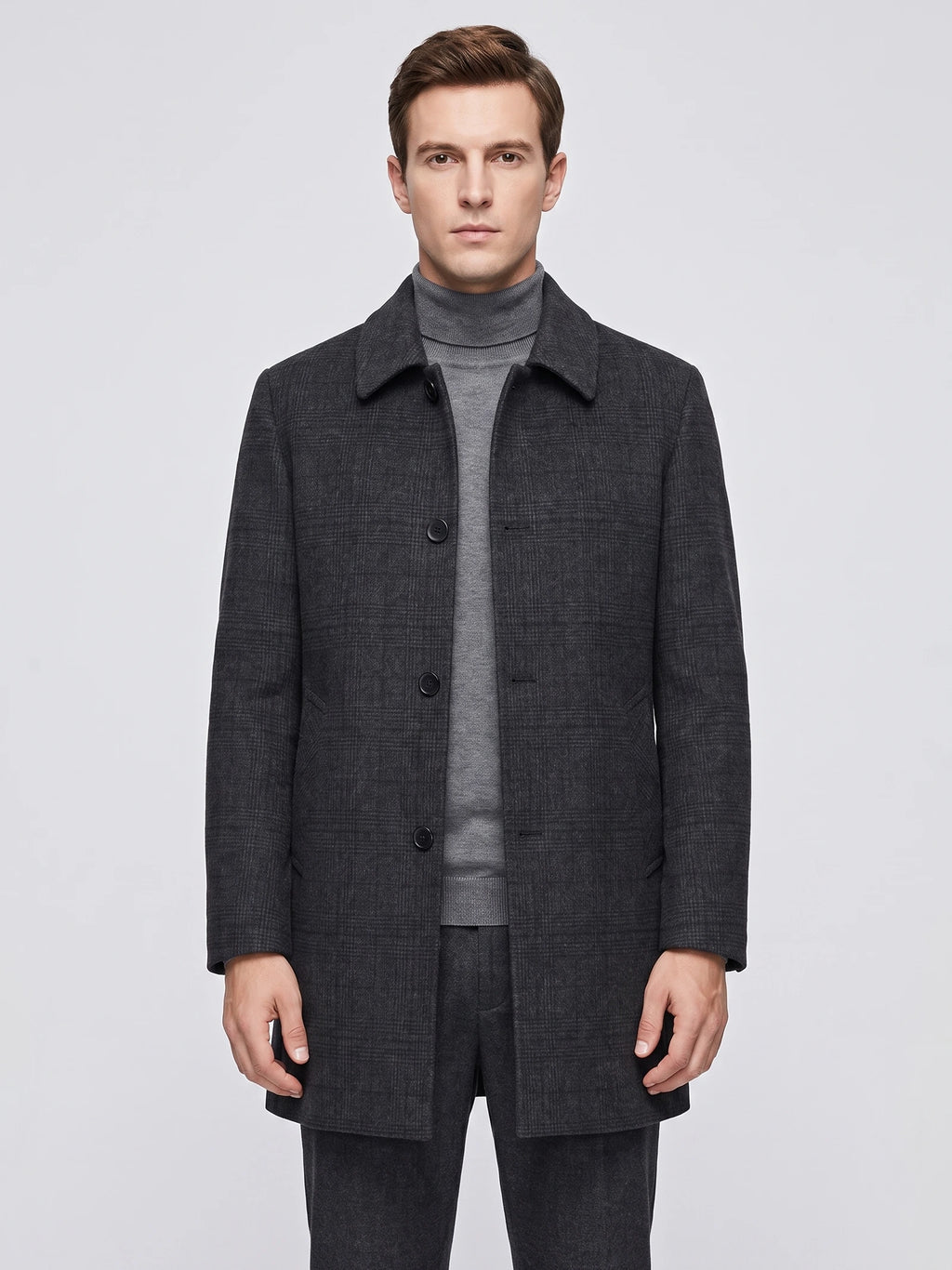 Front studio view of a model wearing a Black wool trench coat with a pointed collar, button front, and angled pockets.