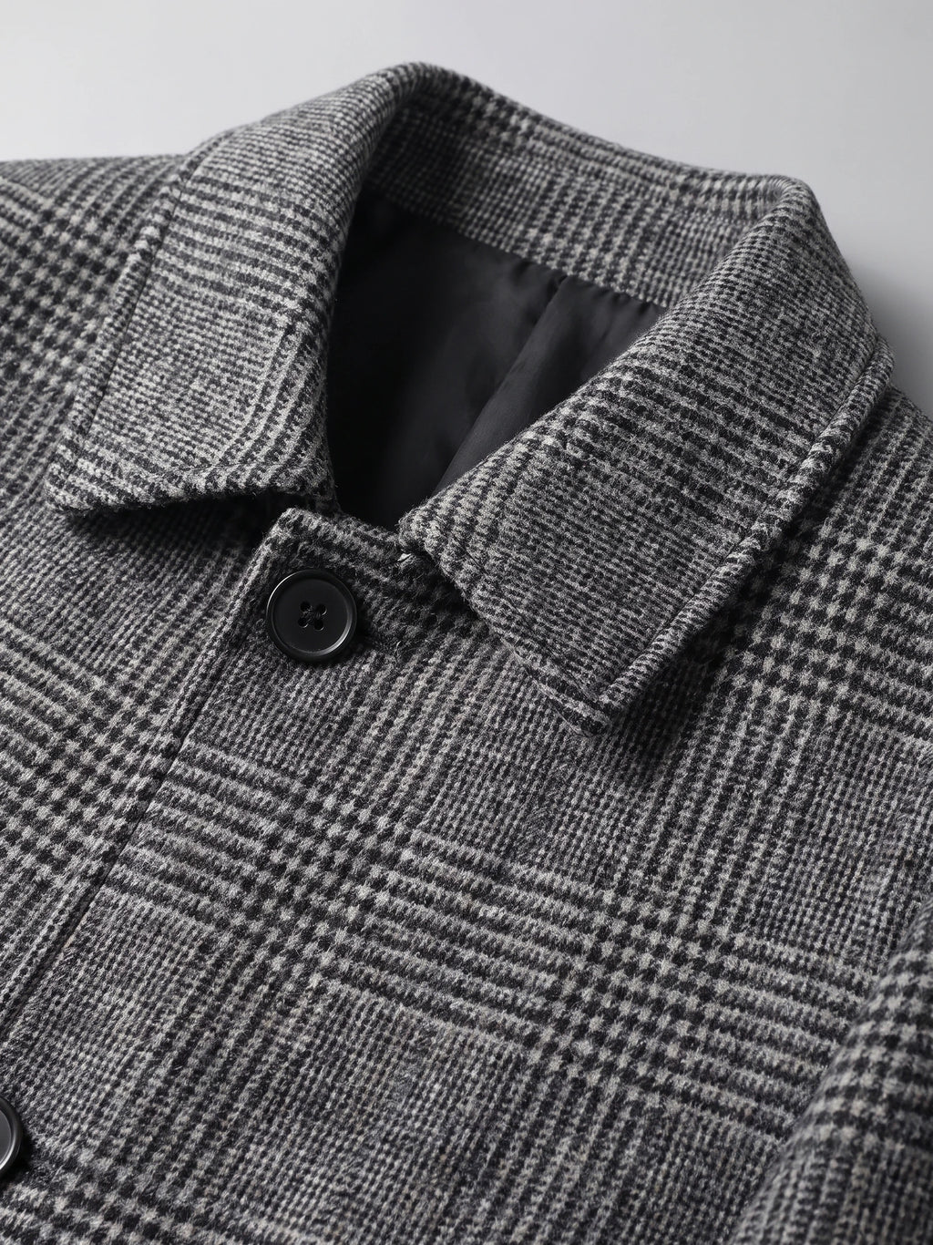 Close-up of the Gray Wool Trench Coat showing its notched collar, plaid texture, lining, and button closure.