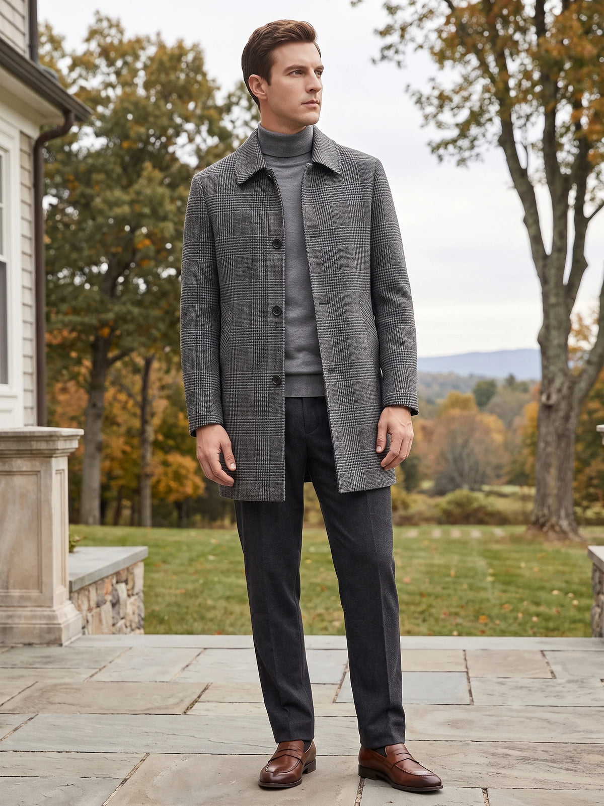 Model wearing a Gray plaid wool trench coat on a stone patio beside an autumn garden.