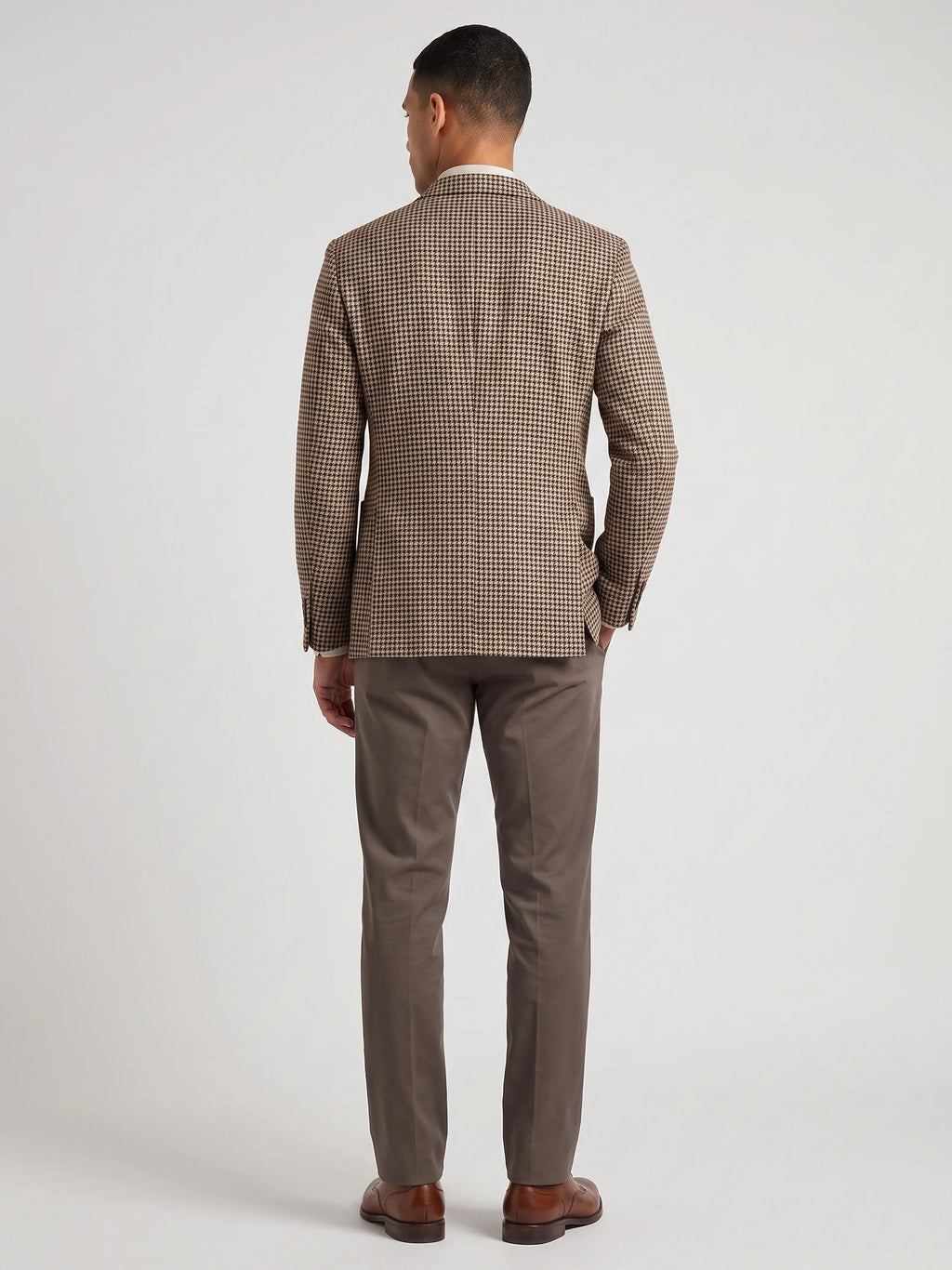 Rear studio view of a model wearing a Brown wool tweed blazer with a houndstooth pattern.