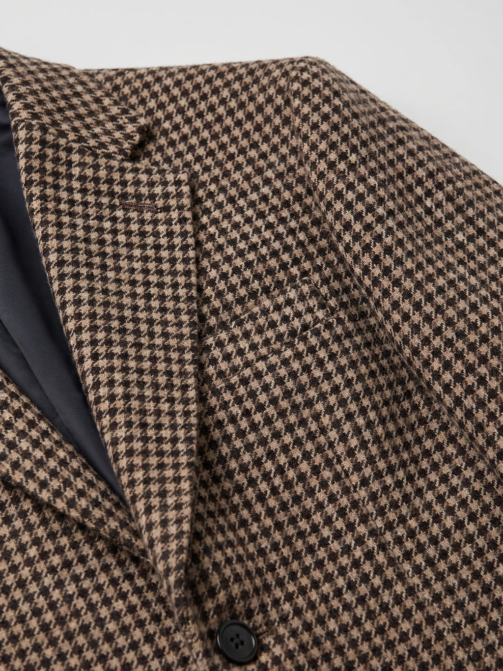Close-up of a Brown Wool Tweed Blazer showing the houndstooth fabric, notched lapel, and front button.