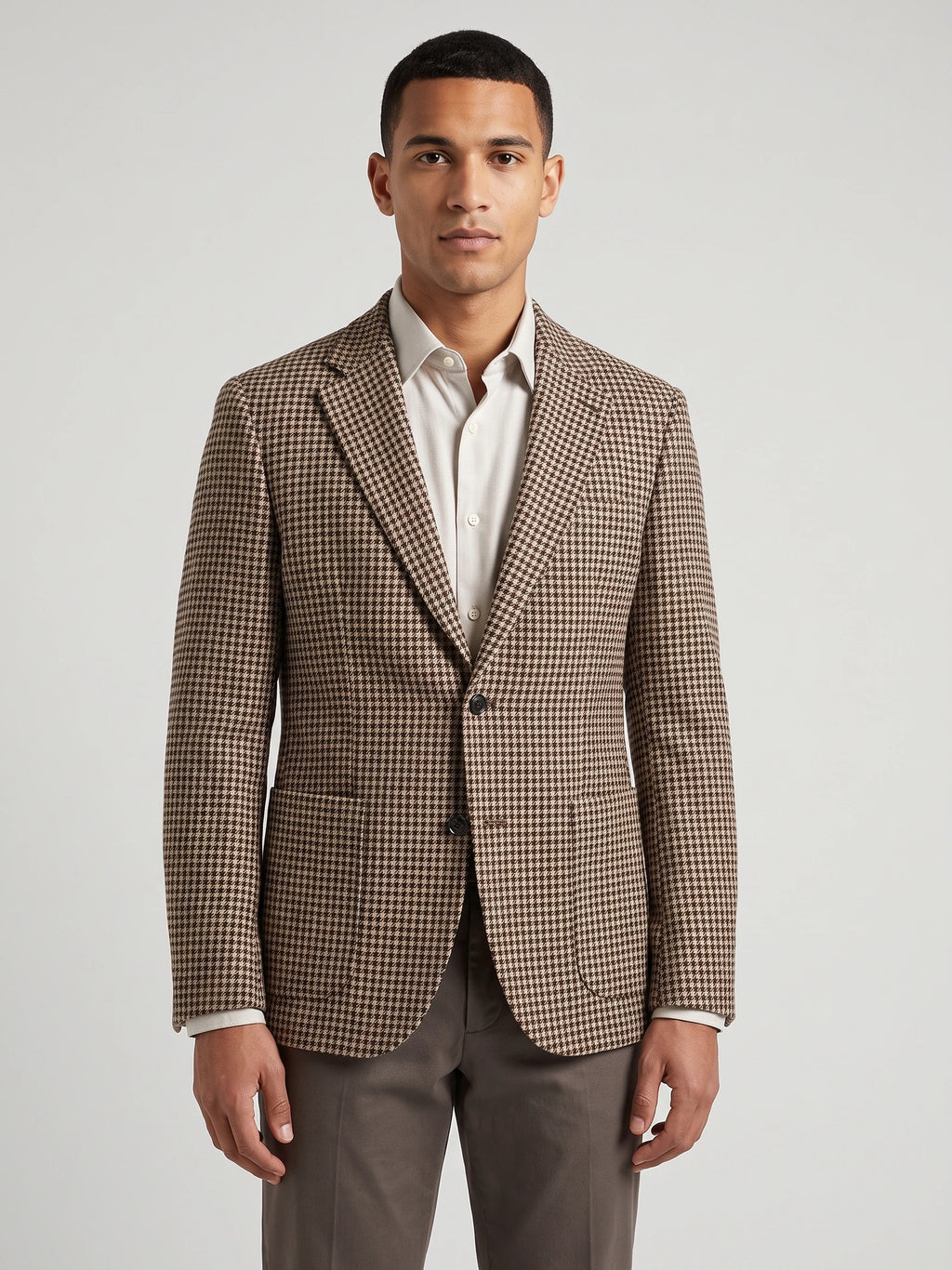 Front studio view of a model wearing a Brown wool tweed blazer with a houndstooth pattern, notch lapels, and flap pockets.