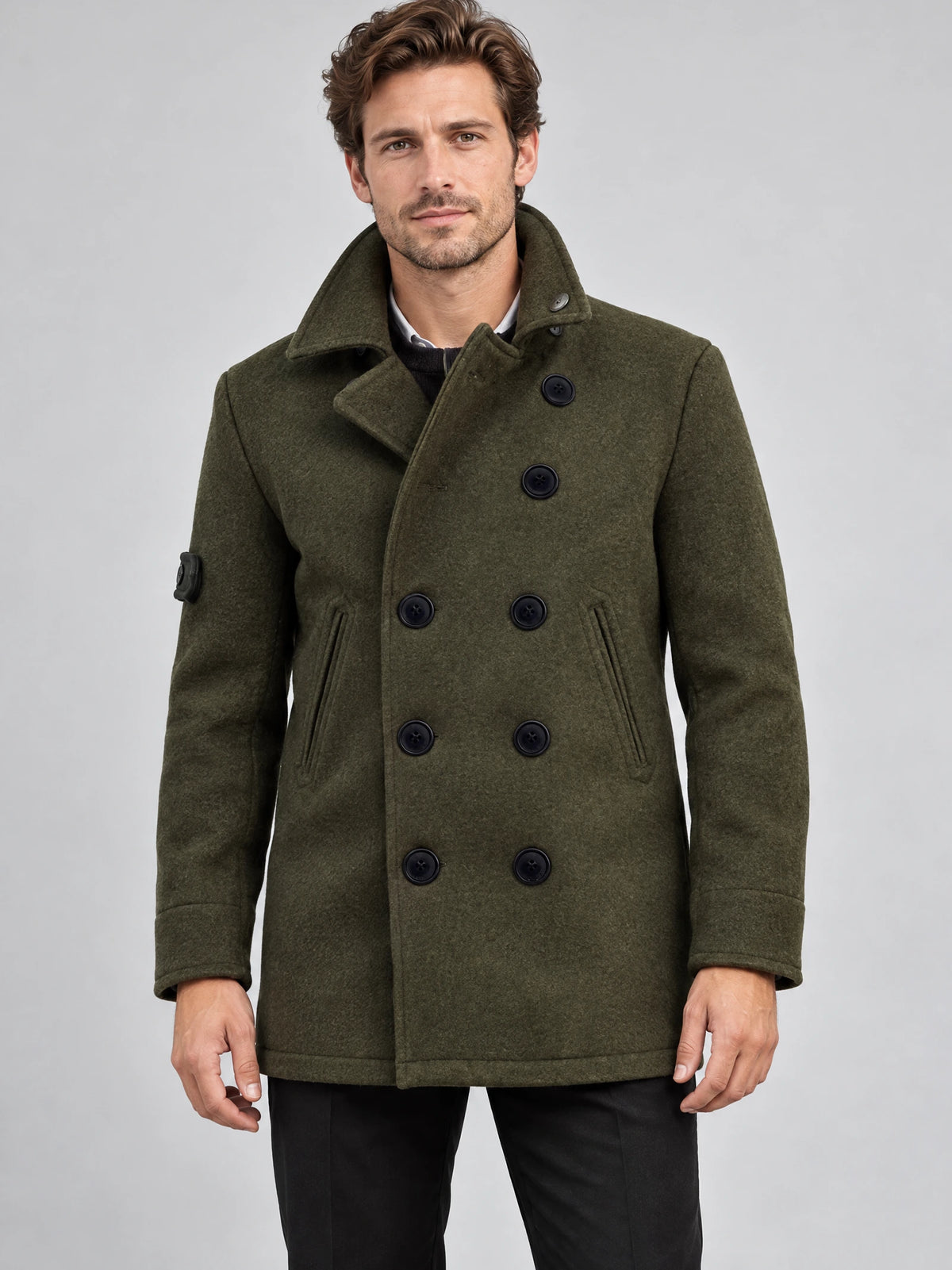 Front studio view of a model wearing a Green wool winter coat with a double-breasted button front, stand collar, and angled pockets.