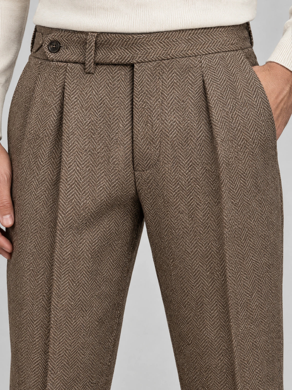 Close-up of Brown woolen herringbone pattern formal pants, showing the buttoned waistband, belt loop, front pleats, and side pocket.