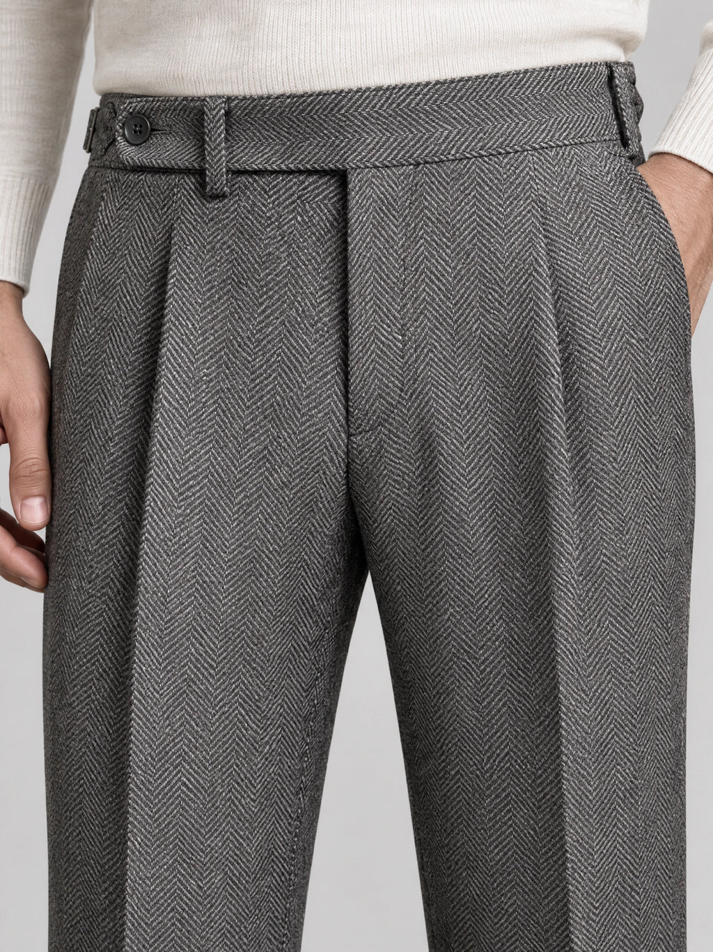 Close-up of Gray woolen herringbone formal pants showing the buttoned waistband, belt loops, front pleats, and side pocket.