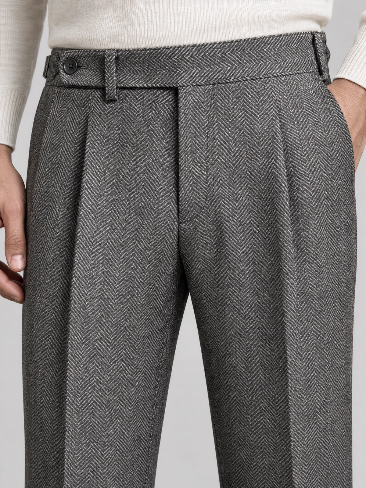 Close-up of Gray woolen herringbone formal pants showing the buttoned waistband, belt loops, front pleats, and side pocket.