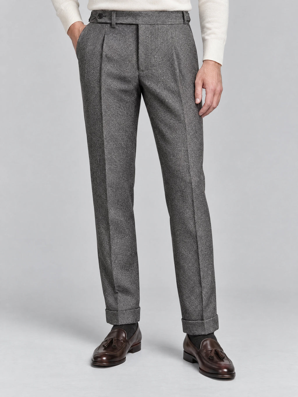 Model wearing Gray woolen herringbone formal pants with front pleats, side pockets, and cuffed hems in a studio.