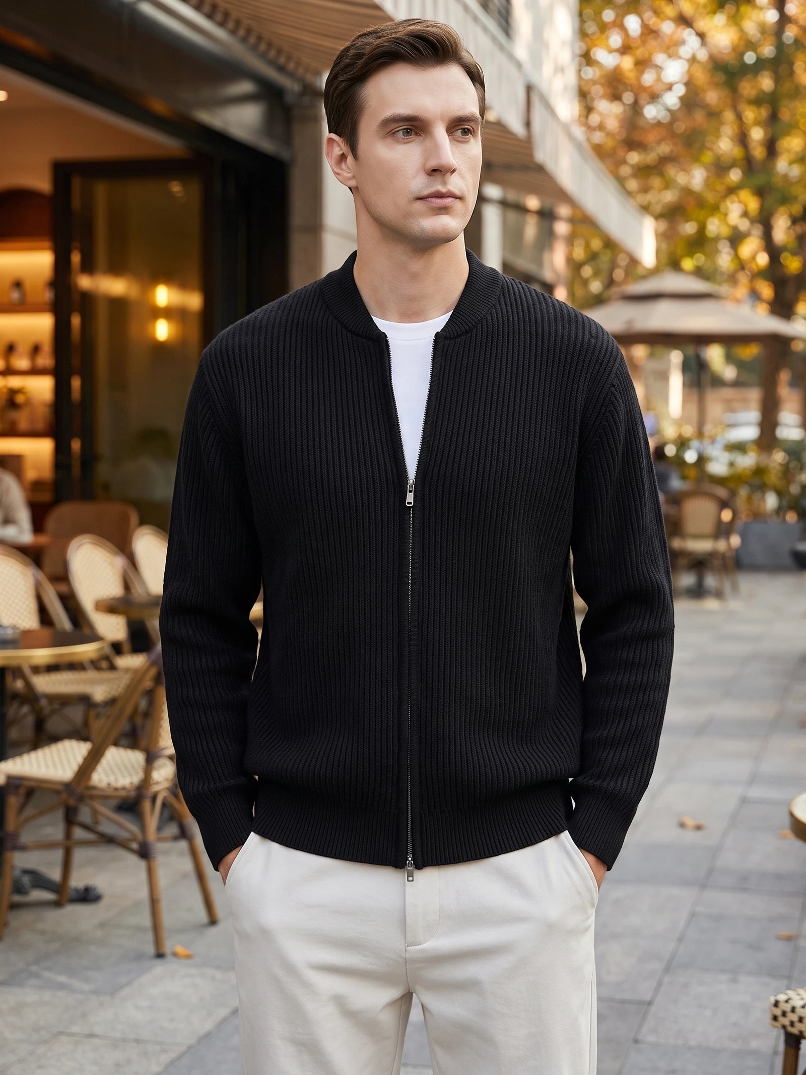 Model wearing a Black ribbed zip up cardigan with a stand collar outside a café.
