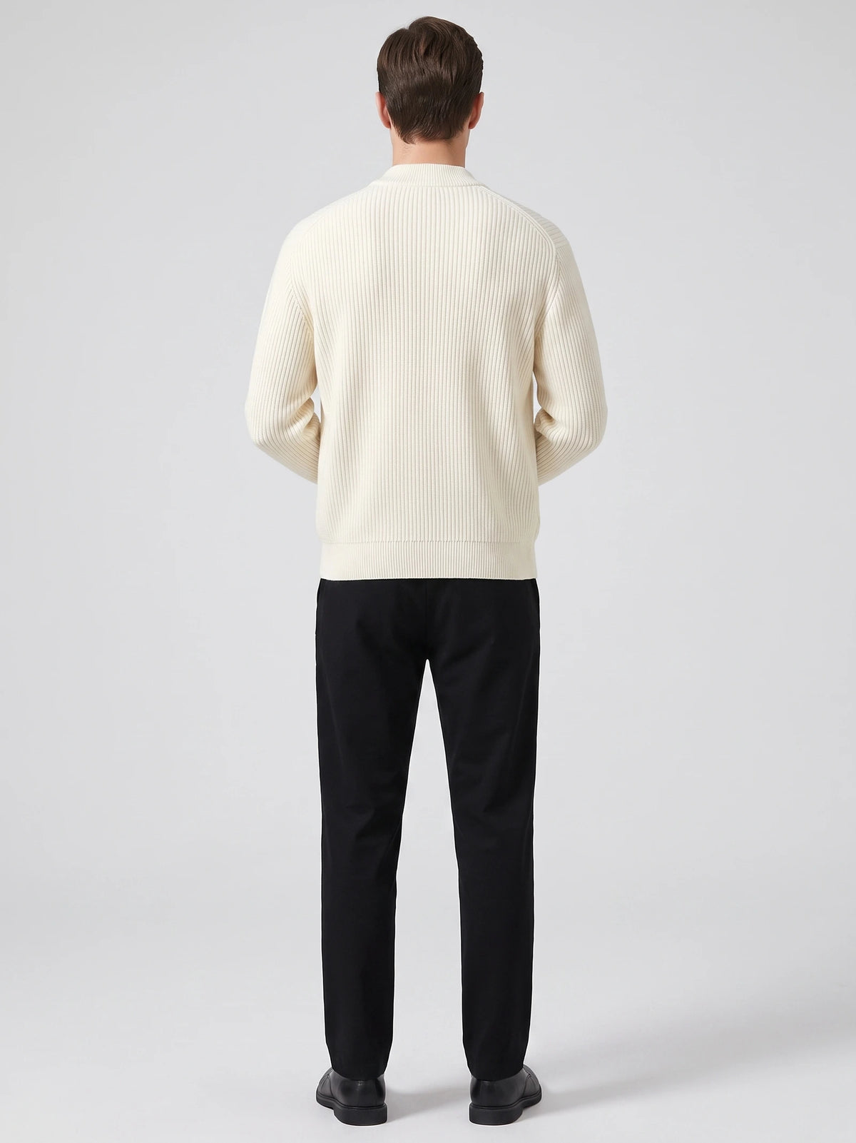 Rear studio view of a model wearing a White zip up cardigan with vertical ribbed knit texture and a stand collar.