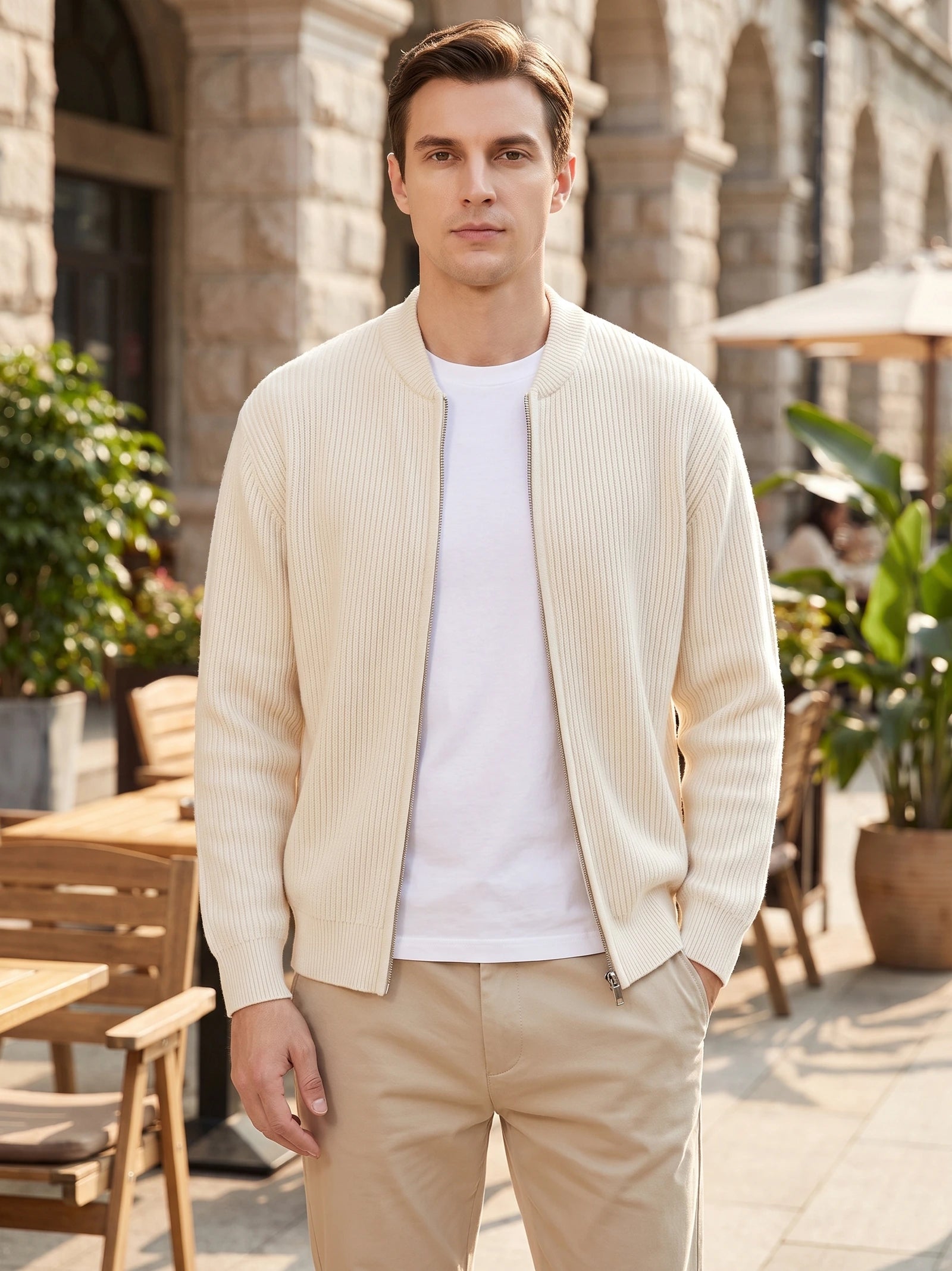 Man wearing a White ribbed zip up cardigan with a stand collar at an outdoor café.