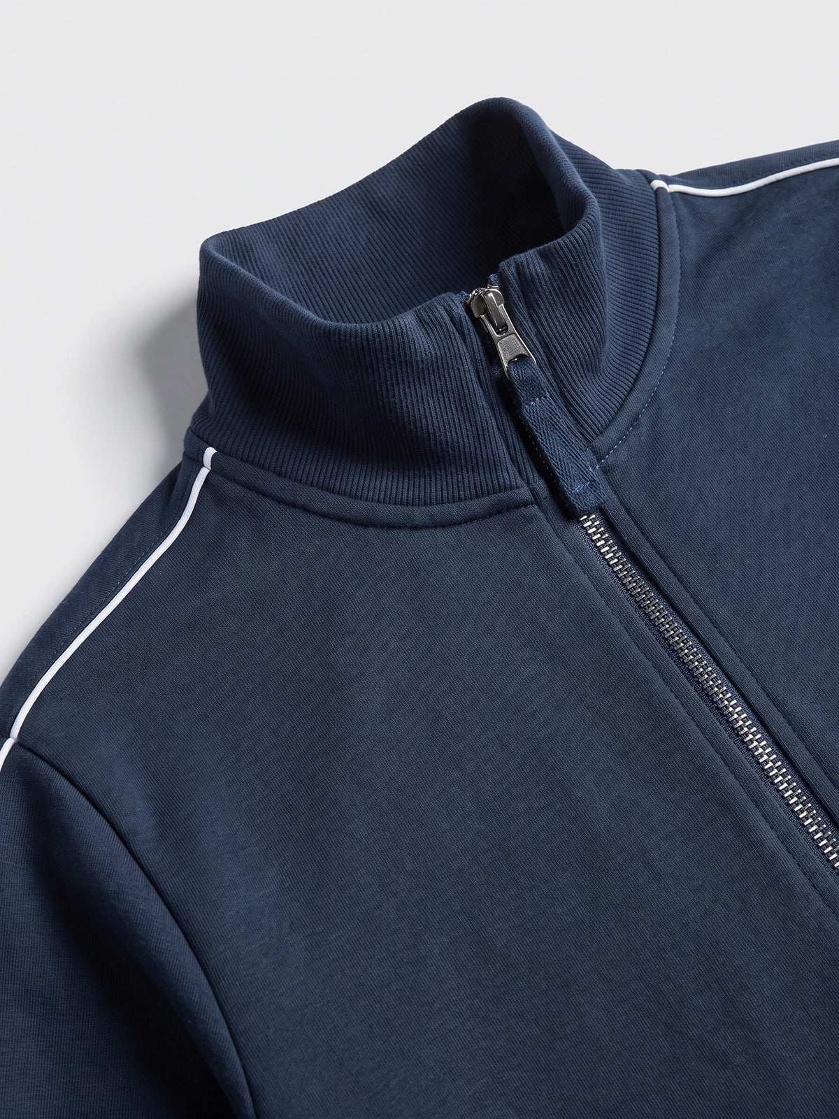 Close-up of the Navy Zip Up Sweater with a ribbed stand collar, front zipper, and contrast shoulder piping.